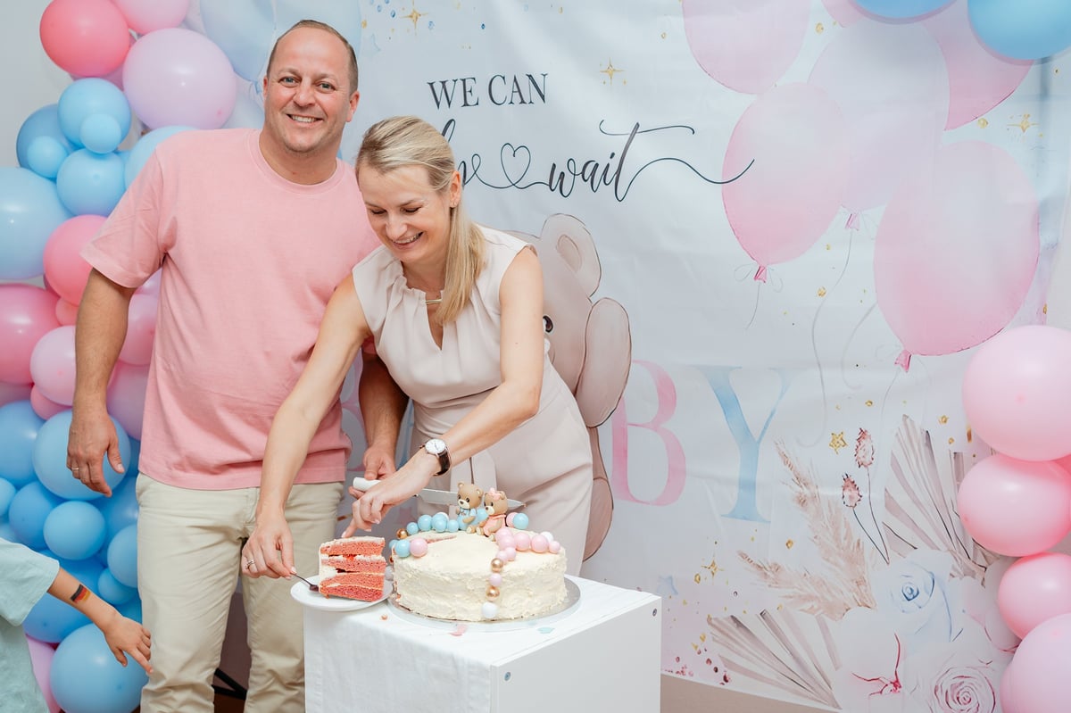 Couple cutting cake at gender reveal celebration