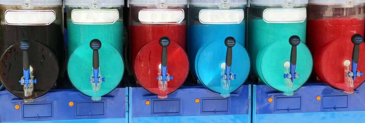 Colorful shaved ice flavors at a carnival snow cone station